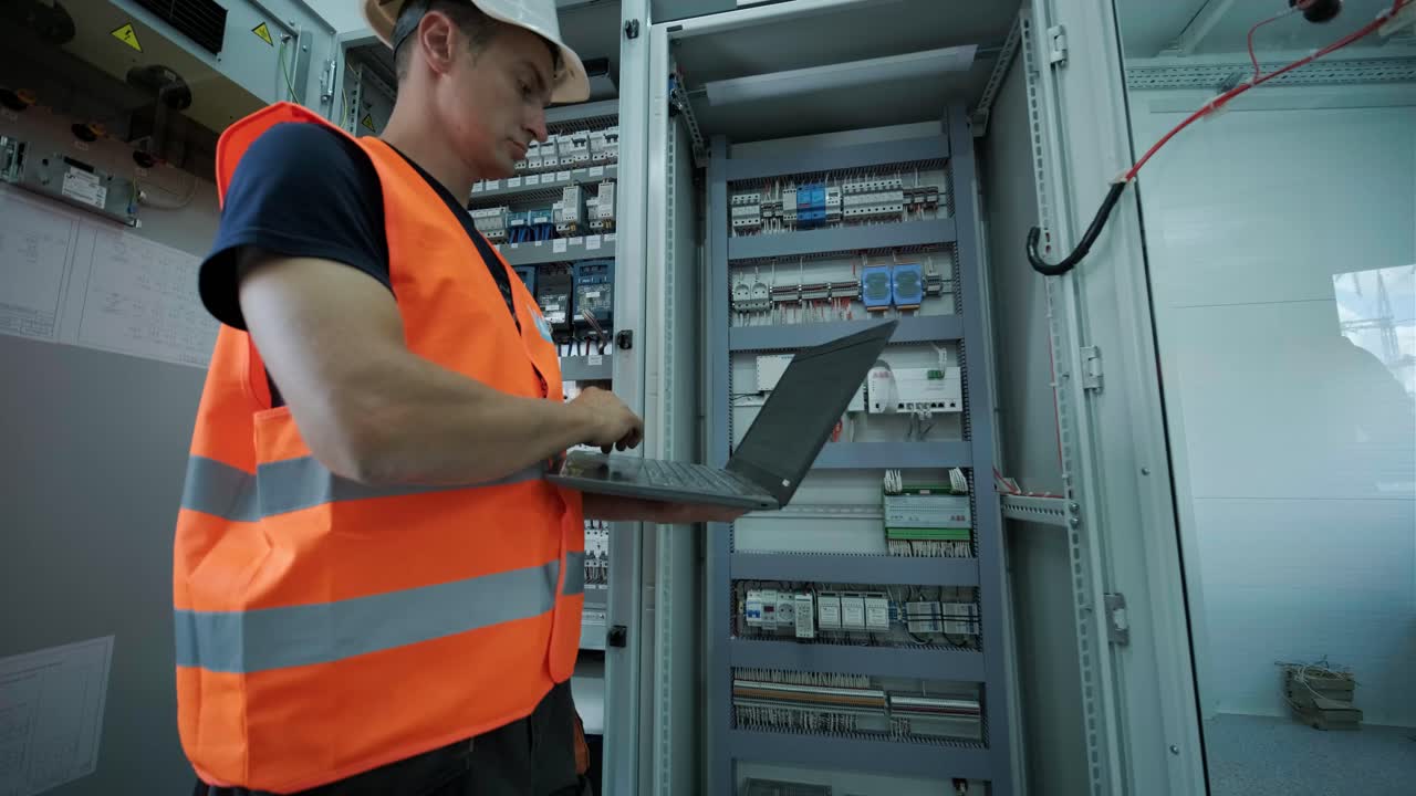 el ingeniero eléctrico que trabaja comprueba la tensión de corriente eléctrica y la sobrecarga en la parte delantera del gabinete del centro de carga o de la unidad de consumo para el mantenimiento en la sala principal del sistema de distribución de energía.