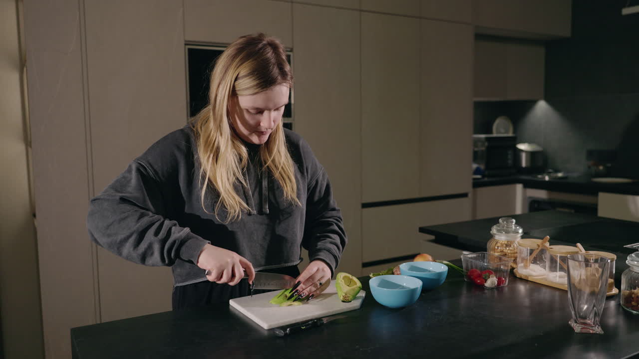 Kvinde skærer avocado i køkkenet.