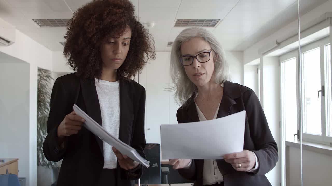 Business women with documents standing and talking in office