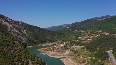 Flying-up-between-the-hills-in-the-mountains-with-river-and-road-in-sight