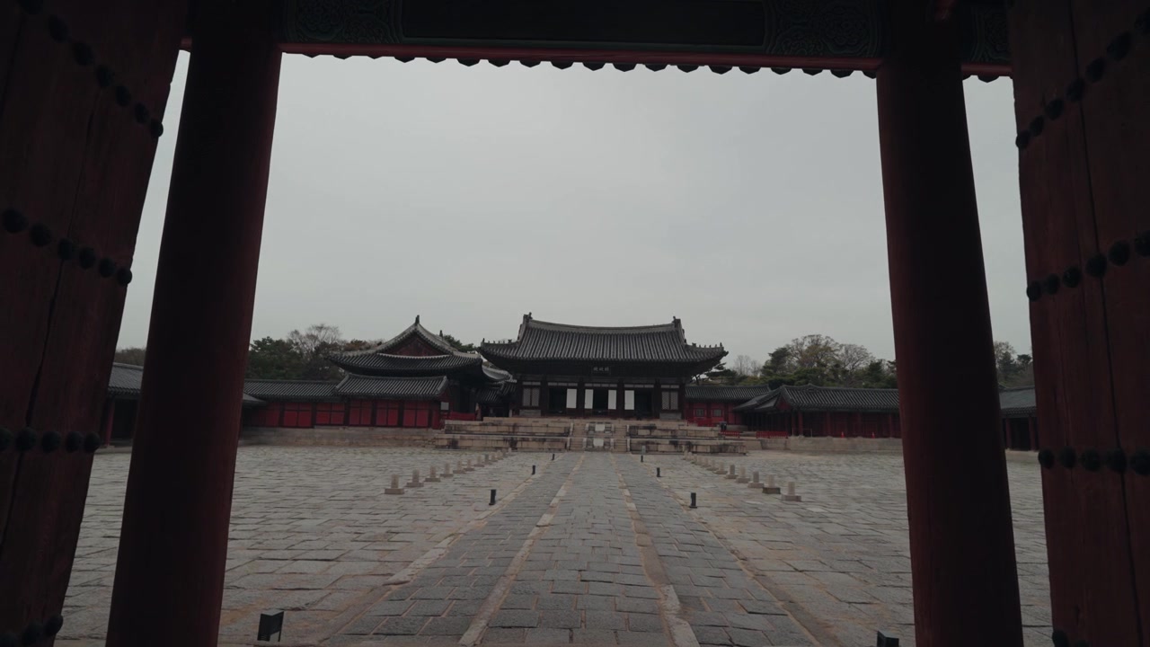 Vista di un cortile di un palazzo tradizionale coreano attraverso un cancello rosso.