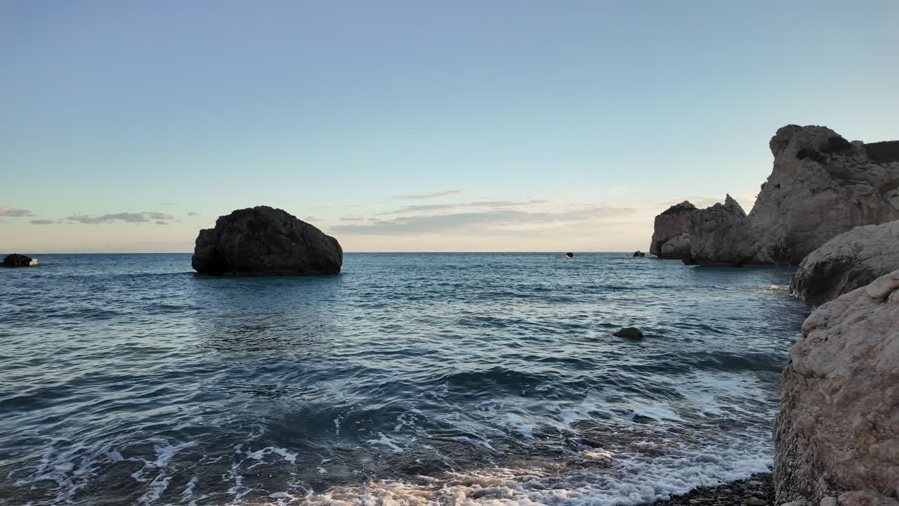 una vista serena de la costa de chipre, con formaciones rocosas en el mar y una superficie de agua tranquila, capturada en cámara lenta - colinas de afrodita