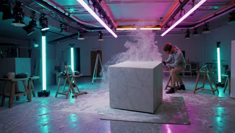 sculpting a marble cube in a neon studio