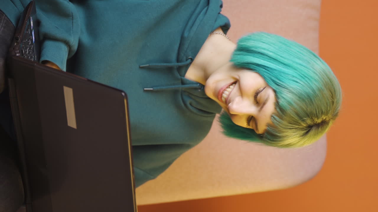 video vertical de una mujer joven hablando en una computadora portátil.