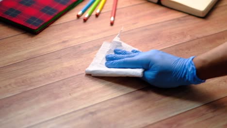 cleaning a wooden desk with gloves