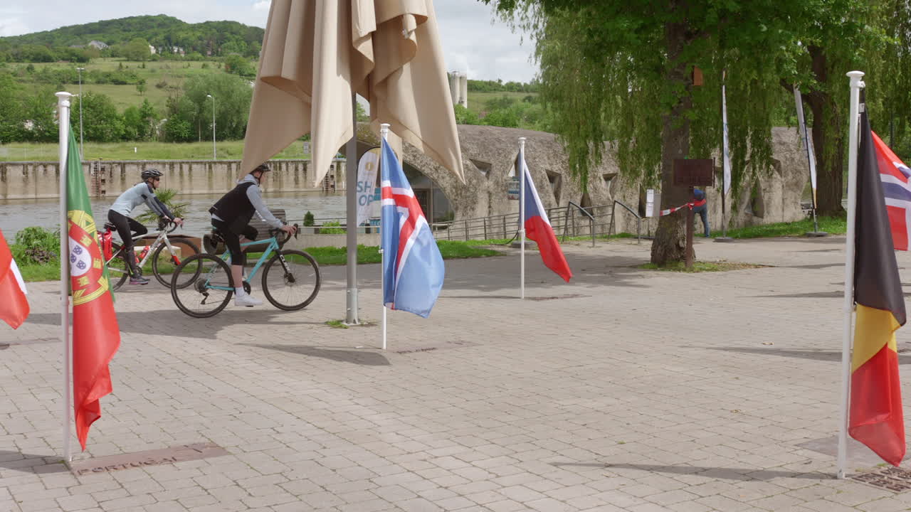 Flags representing European nations flutter outdoors near the Schengen Agreement signing site.