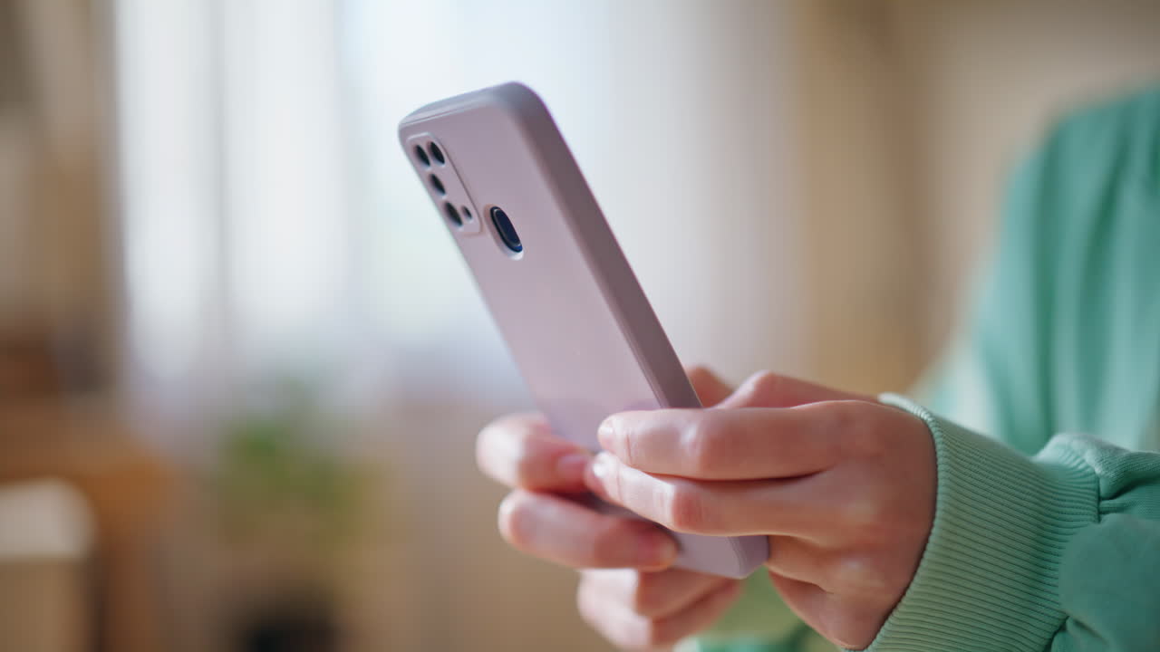 Lady hands texting cellphone in modern living room closeup. Smiling woman