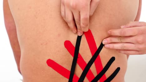 Red-and-black-kinesio-tape-being-applied-to-back