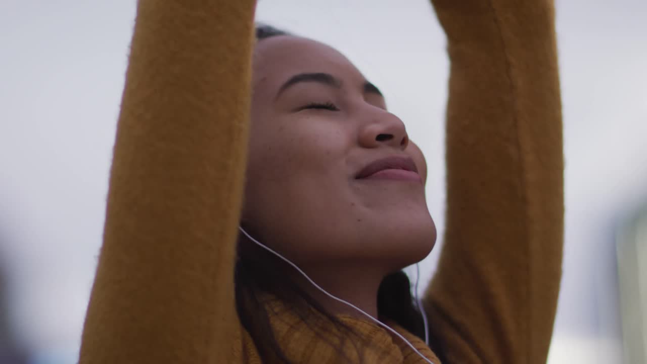mulher asiática usando fones de ouvido ouvindo música e sorrindo