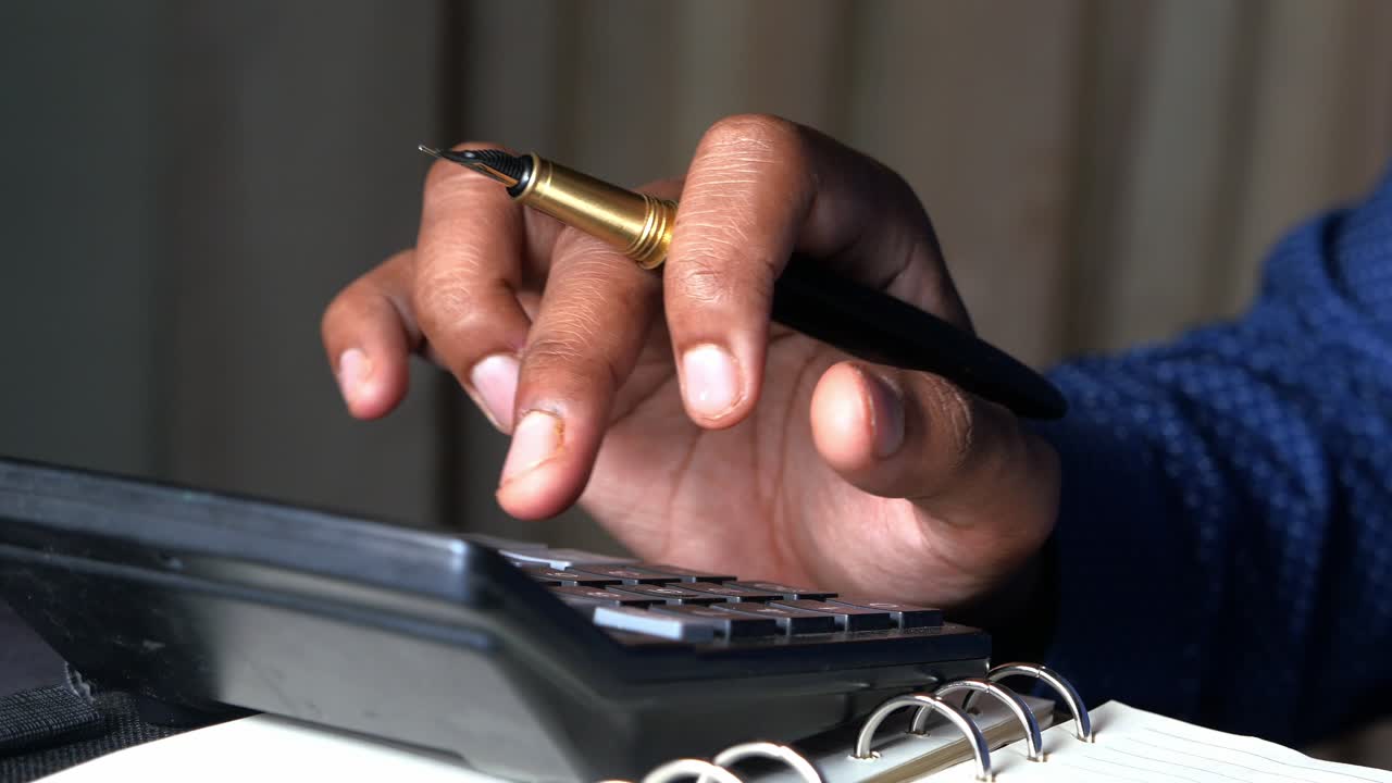 persona que hace cálculos con calculadora y bolígrafo