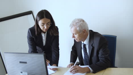 serious female assistant asking male boss about document