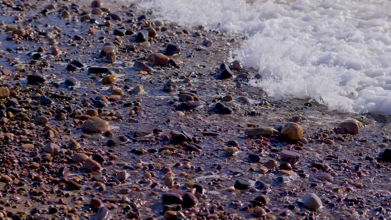 The tide comes in over pebbles on the beach