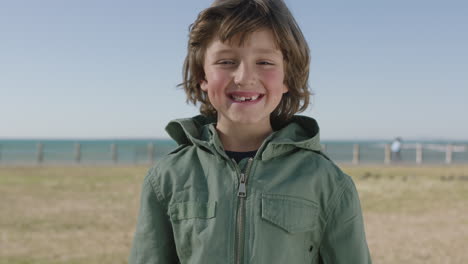 portrait of cute happy boy smiling cheerful at camera enjoying fun day on seaside beach park