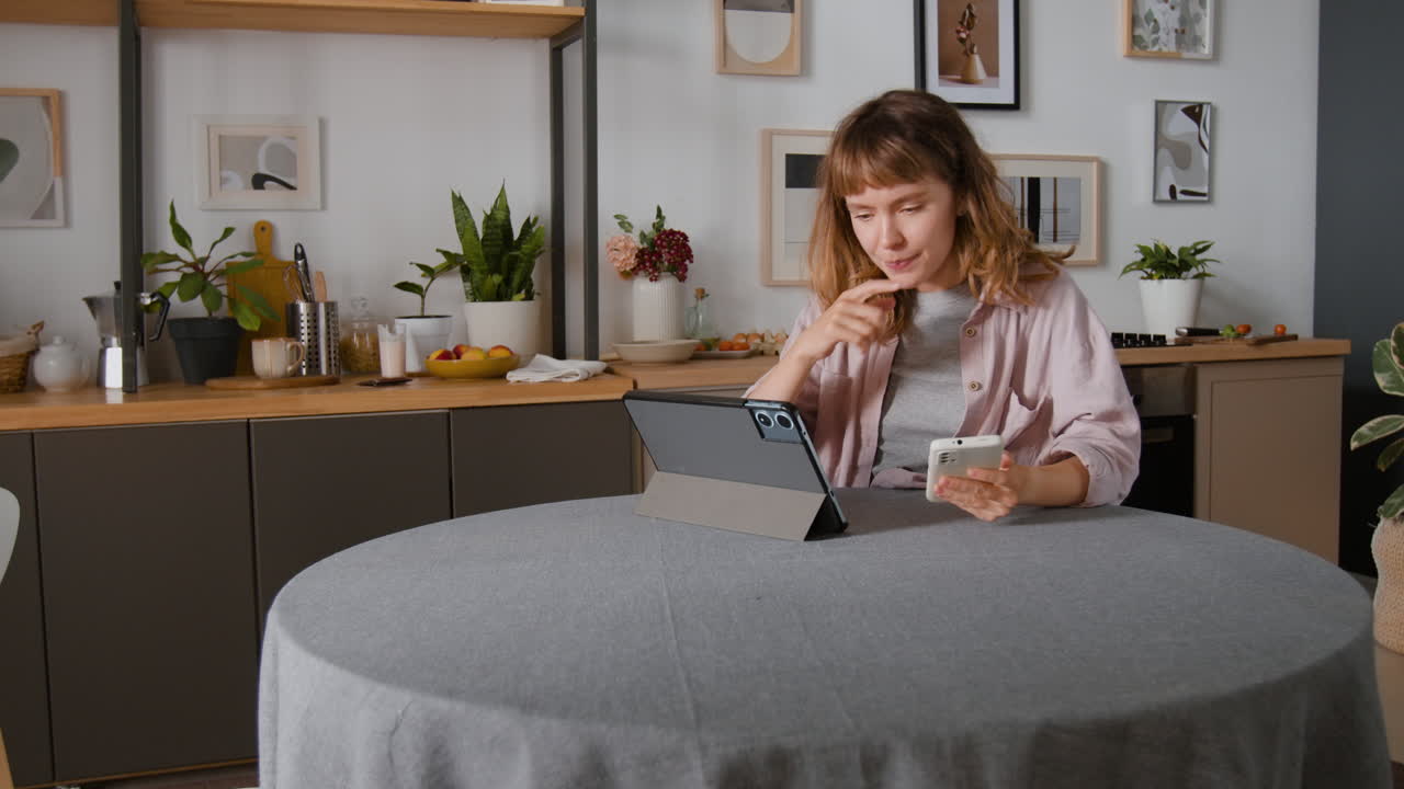 Donna che usa tablet e telefono cellulare in cucina