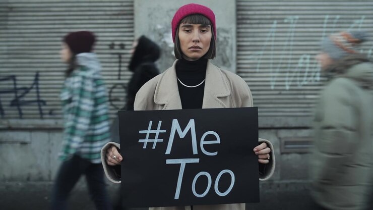 Giovane donna che tiene un cartello #MeToo in un contesto urbano affollato