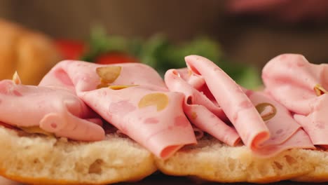 preparing a sandwich with prosciutto and basil