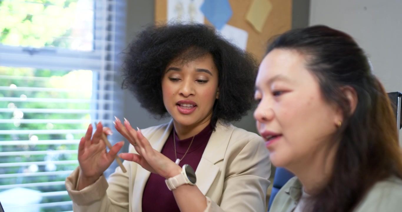 Diverse coworkers front speaker initiating meeting, blazer woman pointing at laptop reviewing data