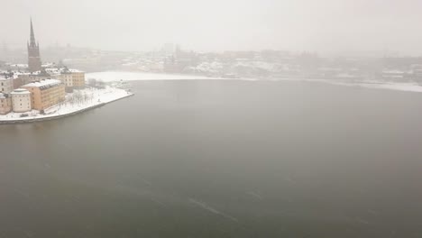 Wide-aerial-panning-view-over-city-skyline-on-drab-and-grey-winters-day