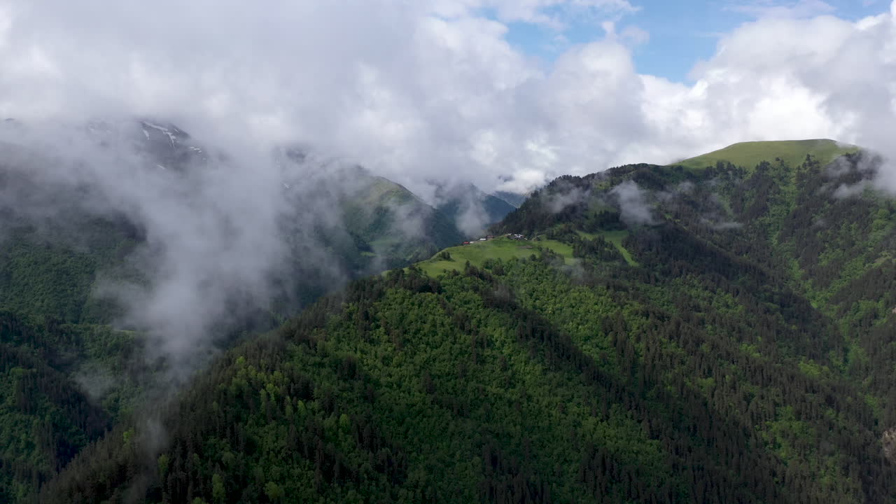 amplio dron giratorio cinematográfico disparado a través de las nubes de un pequeño pueblo en la cima de una montaña en el pueblo de tusheti en georgia