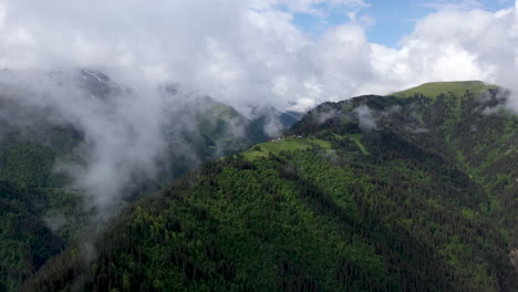 wide cinematic rotating drone shot through the clouds of a small village on a mountain top in tusheti village in georgia