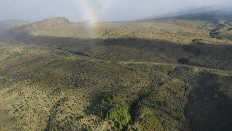 Aerial-view-of-a-colorful-rainbow-over-Haleakala-Highway-on-slopes-of-volcano,-Maui,-Hawaii