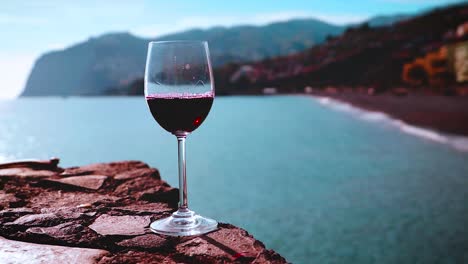 red wine poured into wine glass overlooking beach with mountains, madeira