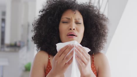 woman with tissue sneezing at home