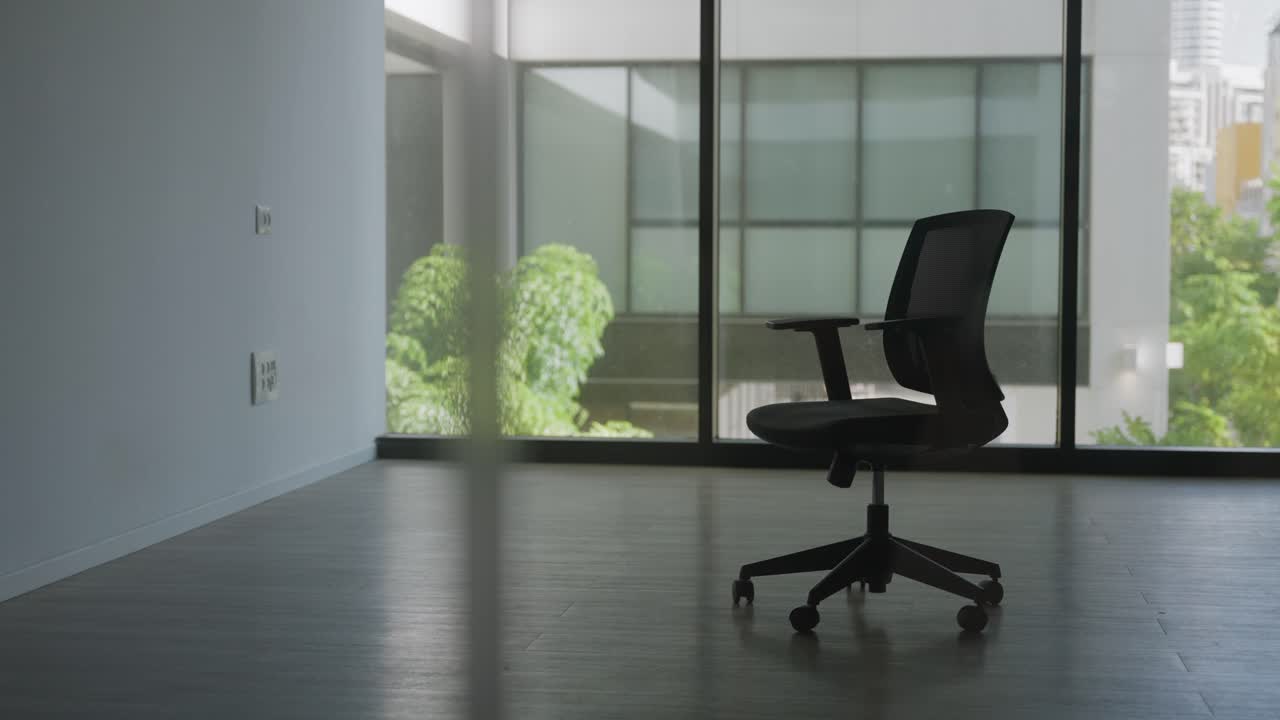 Office chair in vacant room with glass windows in modern office building. New place to move in or leaving it behind. Bankrupt foreclosure. No people inside. Going out of business default on payment