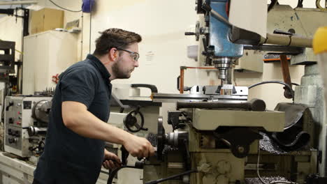 tecnico che controlla e installa una macchina di fresatura professionale per il taglio e la perforazione di prodotti metallici di precisione