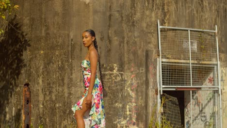 Sexy-model-stands-at-the-base-of-a-radar-tacking-station-in-a-long-flower-dress-before-looking-up