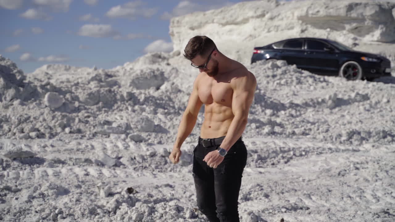 Young muscular bearded man. Sexy caucasian fit man posing on nature