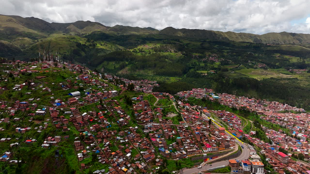 Panoramico filmato aereo con drone del vasto paesaggio urbano di Cusco, Perù. Vista panoramica di fitte case con tegole rosse che si arrampicano sulle verdi colline delle Ande. Contesto storico della capitale Inca