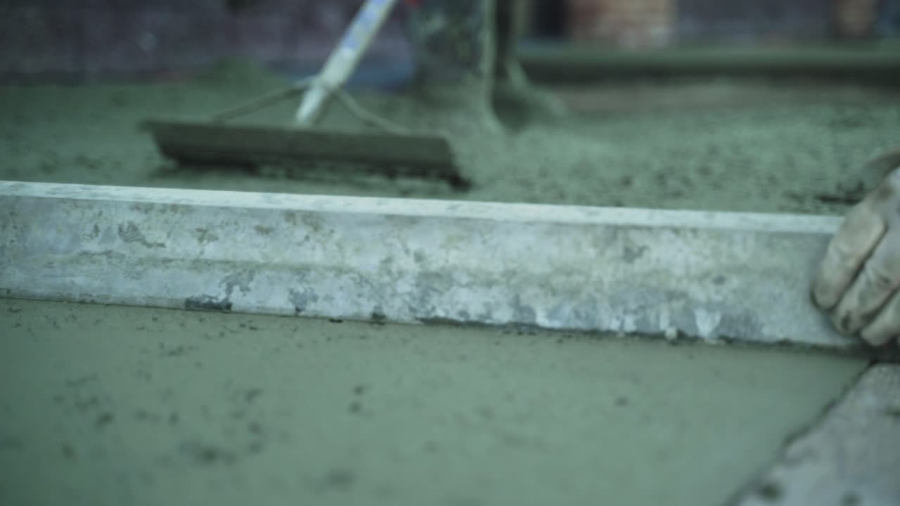 근접 사진, 건설 노동자 들 이 시멘트 보행자길 을  ⁇ 고 평준화 하는 것, 느린 움직임