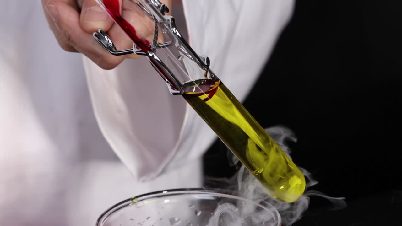 A test tube with liquid changes color during a chemical reaction, observed closely by a scientist.