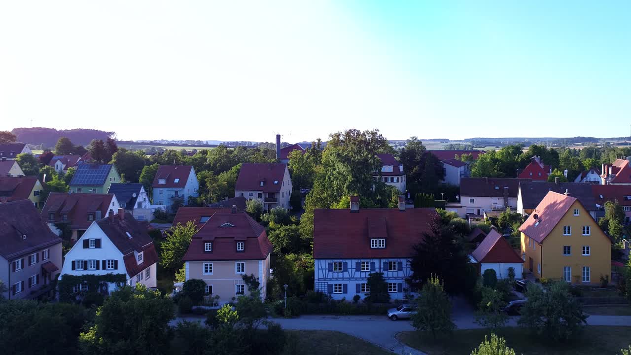een drone vliegt langzaam tegen huizen aan bij het begin van de zonsondergang
