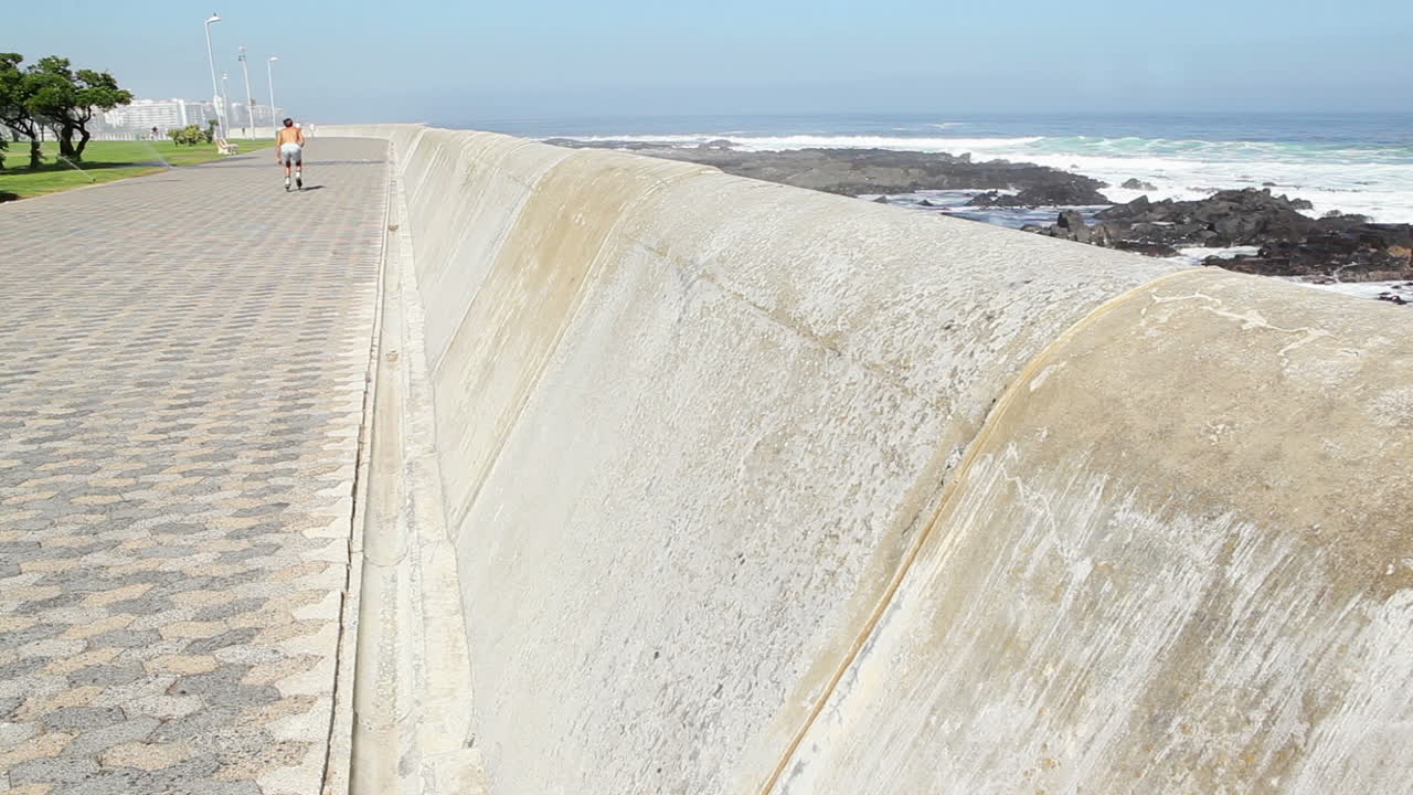Uomo in forma che pattina in linea lungo la costa