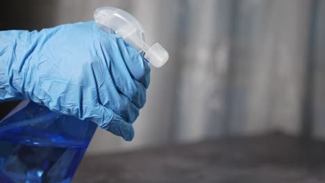 person cleaning with spray bottle and blue gloves