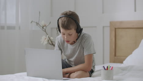 homeschooling for little child boy kid is drawing by felt pens and listening teacher by headphones