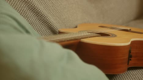 close up one classical wooden guitar on a sofa, music instrument camera movement