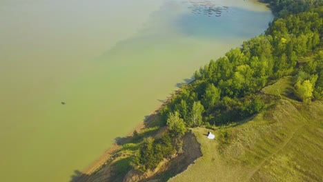 young-family-on-steep-bank-with-forest-at-river-aerial-view