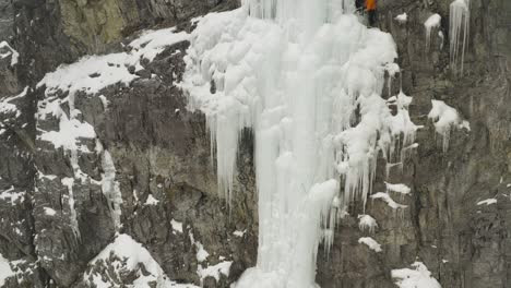 Increíble-Vista-Aérea-Escalador-De-Cascada-Congelada-En-Cornisa-Ayudando-A-Un-Amigo