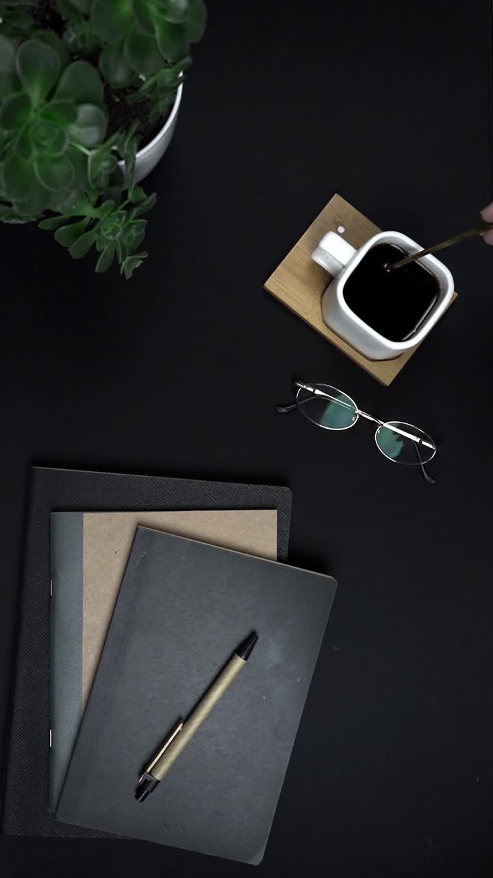 Oversiktsbilde av hånd som rører kaffe på et minimalistisk skrivebord