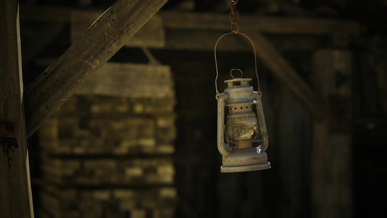 Lampada a olio tremolante che illumina travi impolverate e ragnatele in soffitta