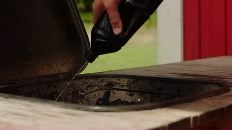 unrecognizable man have lighter fluid on the bbq or barbecue grill and lights it with a match in sweden on a warm summer day
