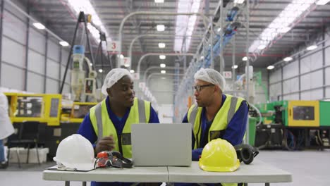 warehouse workers using laptop in factory