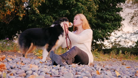 una mujer joven jugando con su perro junto a un lago 3