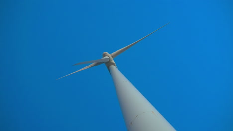 low dutch angle view of wind turbine with clear blue sky on the background