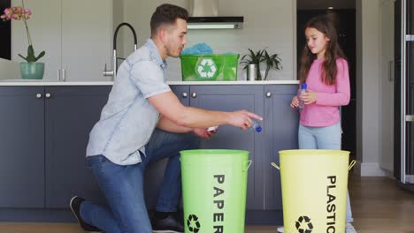 happy caucasian father and daughter segregating rubbish in kitchen