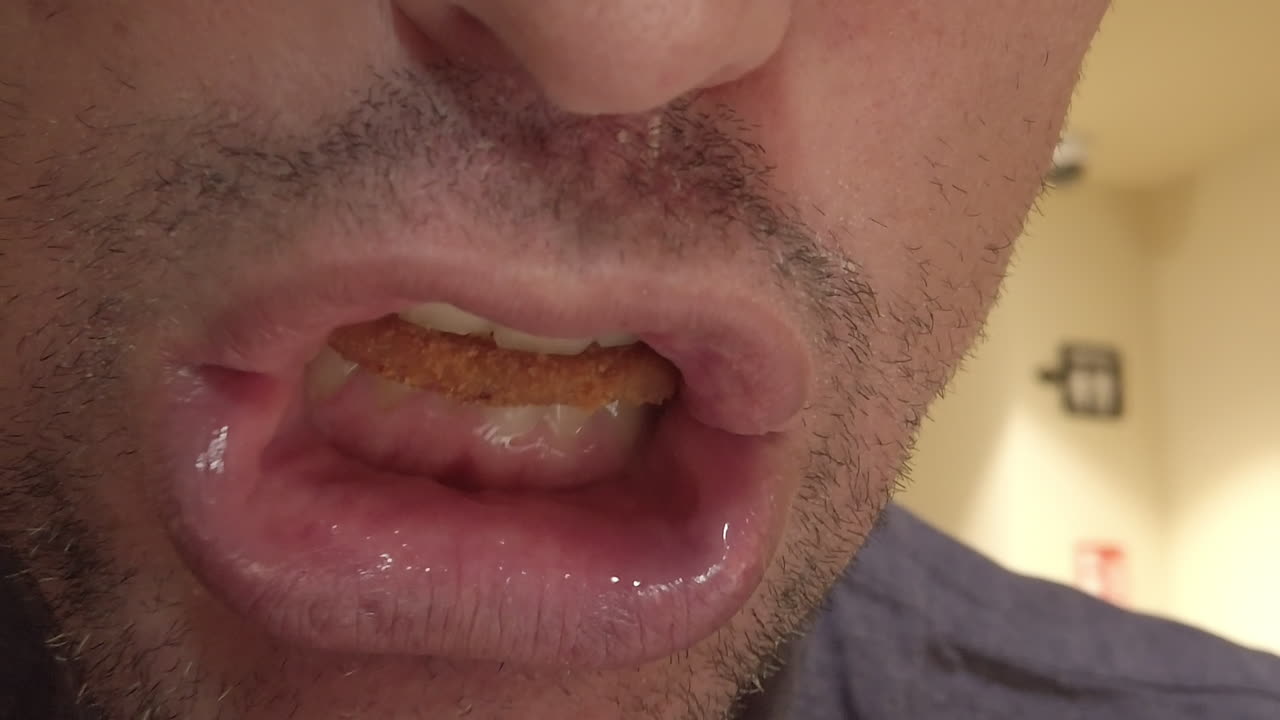 Slow motion close up of a man mouth eating greedily an onion ring