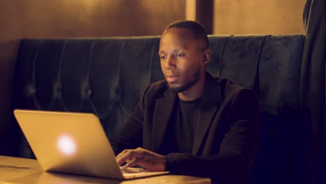 Professional-male-talking-firmly-on-a-video-call-on-his-laptop-in-a-booth